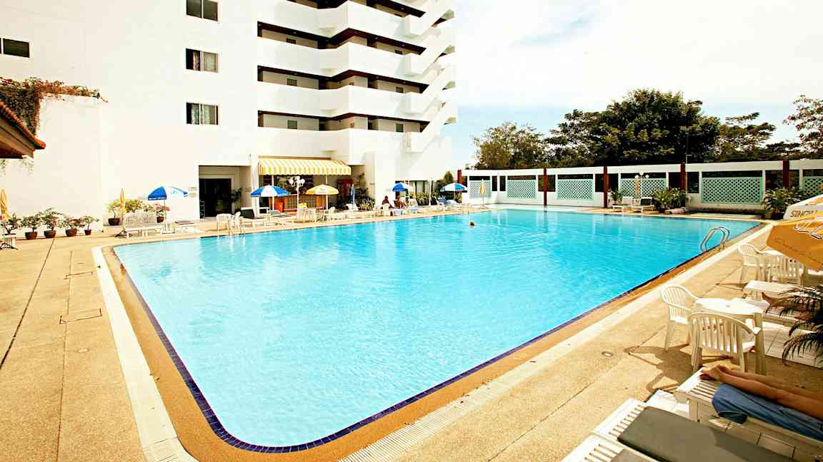 Utomhuspool vid ett hotell med solstolar och parasoller. (AI-genererad text)