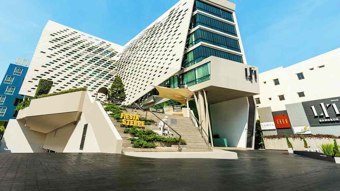 Modern byggnad med unik arkitektur, stora glaspartier och en lutande fasad. (AI-genererad text)