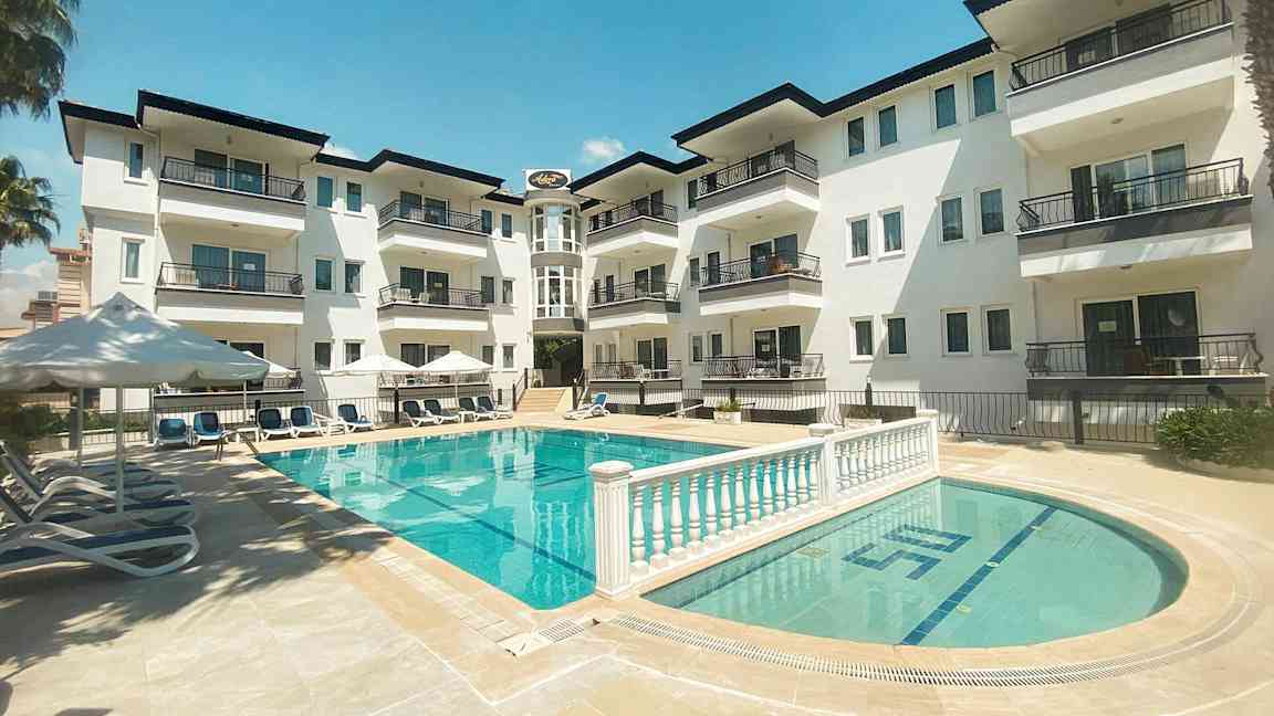 En lägenhetsbyggnad med balkonger mot en poolområde. (AI-genererad text)