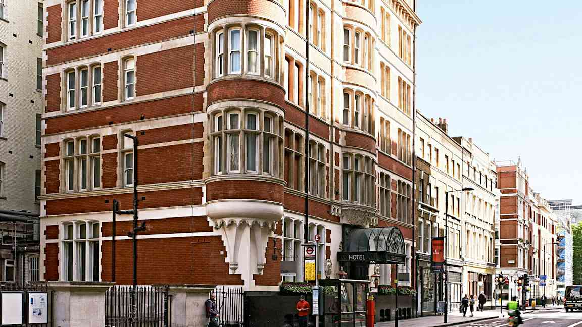 En bild av en röd tegelbyggnad med många fönster och ett hotell på bottenvåningen. (AI-genererad text)