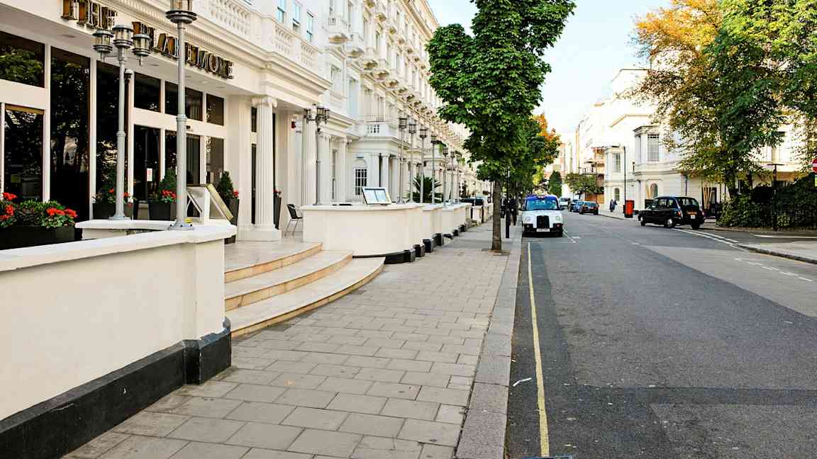 Fasad av ett hotell vid en gata kantad med träd. (AI-genererad text)