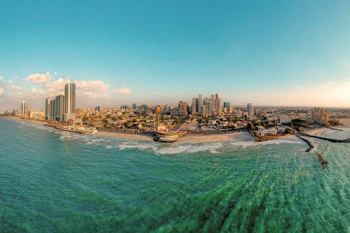 Panoramabild av en kuststad med höghus, strand och hav. (AI-genererad text)