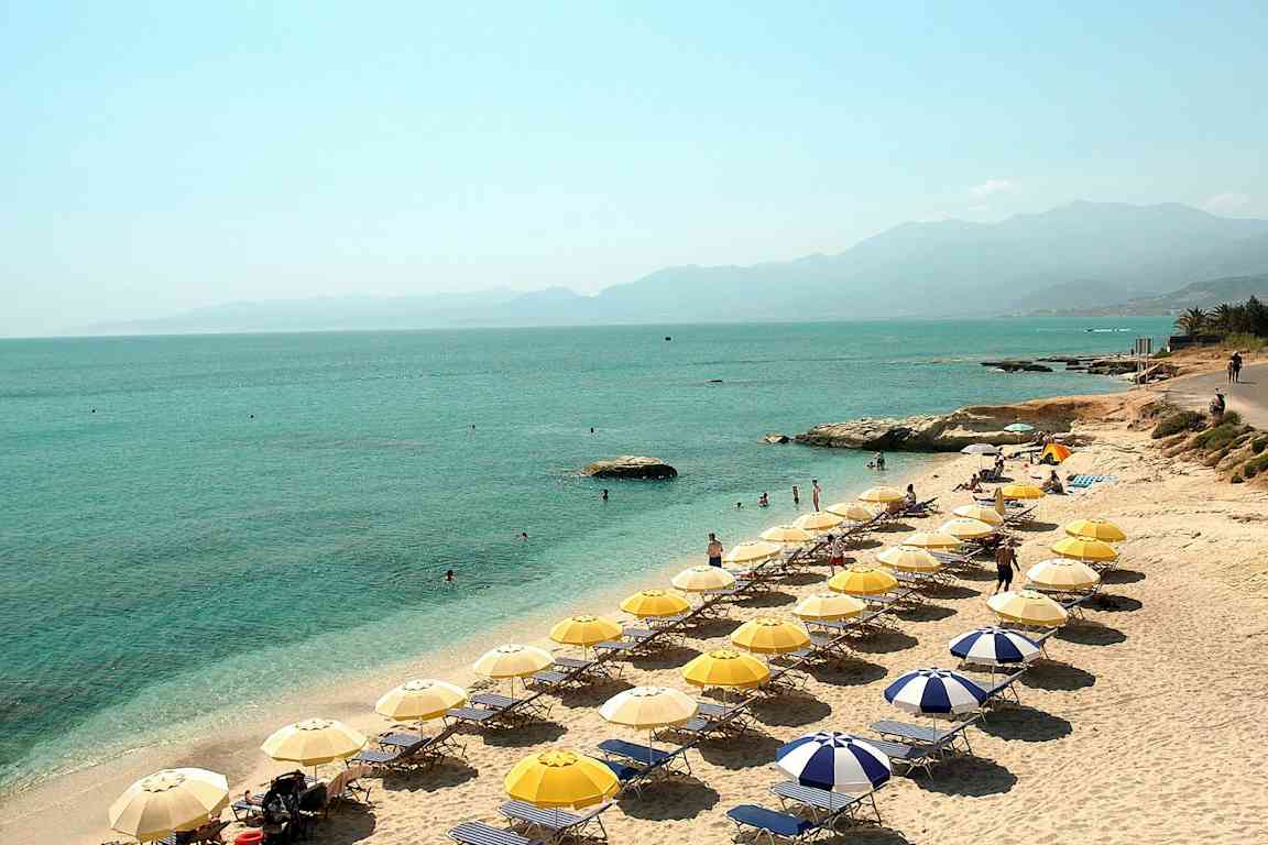 Strand med solstolar, parasoller och människor som solar och badar. (AI-genererad text)