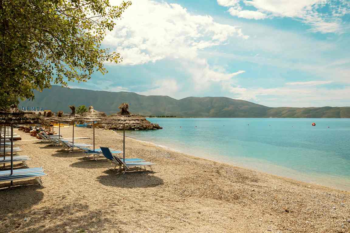 Strand med solstolar och parasoll vid havet. (AI-genererad text)