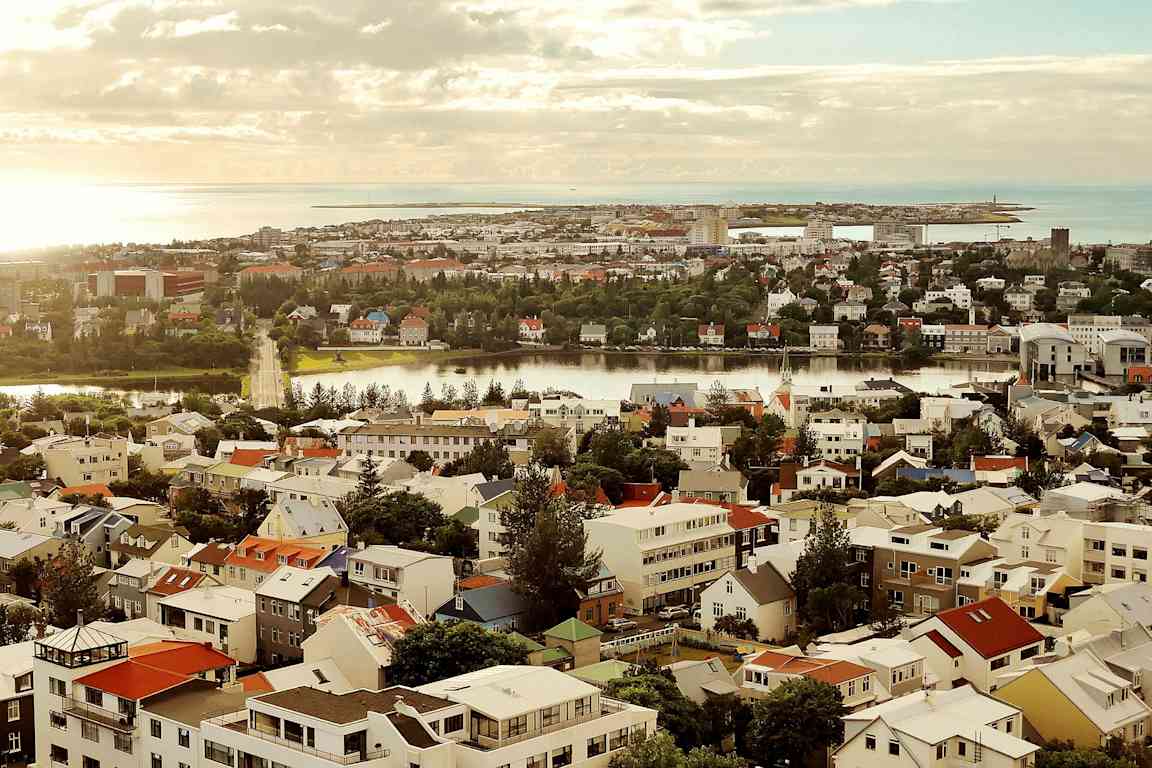 En vy över en stad med många färgglada hus, en flod och en kustlinje i bakgrunden. (AI-genererad text)