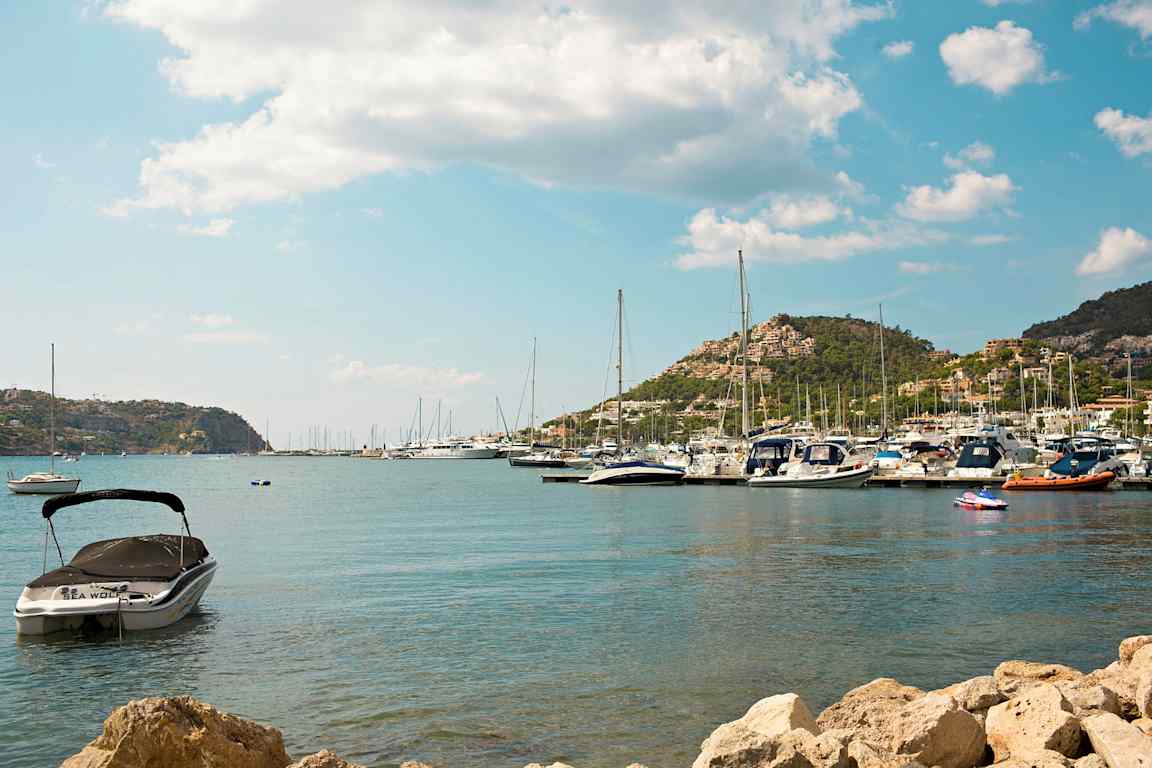 Bild av en hamn med båtar och berg i bakgrunden. (AI-genererad text)