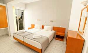 Två enkelsängar med vita sängkläder i ett hotellrum med vitt och träinredning. (AI-genererad text)