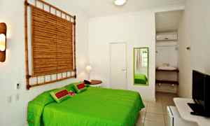 Ett ljust sovrum med en grön säng, en spegel på väggen och bambudekoration. (AI-genererad text)