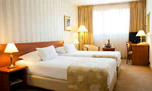 Ett hotellrum med två enkelsängar, lampor bredvid sängarna och ett skrivbord med stol. (AI-genererad text)