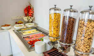 En frukostbuffé med skålar av cerealier, ägg, frukt och kallskuret. (AI-genererad text)