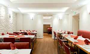 Restaurang med dukade bord och röda stolar. (AI-genererad text)