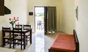 Ett rum med ett matbord och stolar, en bäddsoffa, och en öppning som leder till en balkong. (AI-genererad text)