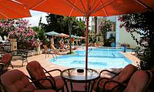 En utomhuspool med solstolar och parasoller runtom, samt sittgrupp i förgrunden. (AI-genererad text)