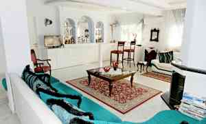 Ett vardagsrum med möbler, inklusive en soffa, ett soffbord, stolar och dekorativa element. (AI-genererad text)