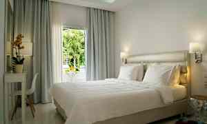 Ljust och modernt inrett hotellrum med en stor säng och fönster med utsikt. (AI-genererad text)