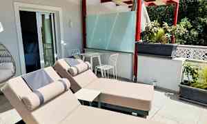 Terrass med två solstolar och ett bord med två stolar under en pergola. (AI-genererad text)