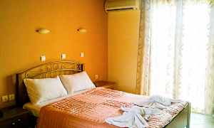 Ett sovrum med en dubbelsäng, orange sängkläder och två handdukar dekorerade på sängen. (AI-genererad text)