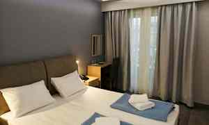 Ett hotellrum med en dubbelsäng, skrivbord och ett fönster med gardiner. (AI-genererad text)