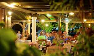 Uteservering med människor sittande vid bord under ett tak. (AI-genererad text)