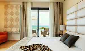 Hotellrum med en säng och havsutsikt från en möblerad terrass. (AI-genererad text)