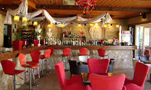 Interiör av en bar med röda stolar och en vägg av sten. (AI-genererad text)