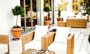 Utomhusmöbler med rotting och vita dynor på en terrass. (AI-genererad text)