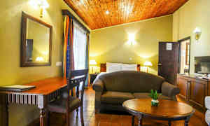 Ett rum med säng, soffa, bord, skrivbord och dekorationer. (AI-genererad text)