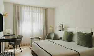 Ett modernt möblerat rum med en säng, skrivbord, stol och fönster med tunna gardiner. (AI-genererad text)