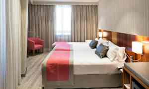 Hotellrum med två separata sängar, enkla moderna möbler och ett fönster i bakgrunden. (AI-genererad text)