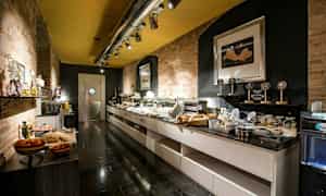 Bufféområde med mat och drycker på flera bänkar, omgivna av tegelväggar och modern belysning. (AI-genererad text)