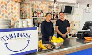 En bar med en disk dekorerad med texten "Tamaragua". På disken finns frukter och porslin. Bakgrunden har hyllor med flaskor. (AI-genererad text)