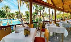 Uteservering med utsikt över en pool och omgivande palmer. (AI-genererad text)