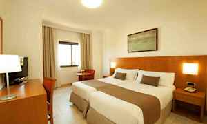 Ett hotellrum med två enkelsängar och träpanel på väggen. (AI-genererad text)