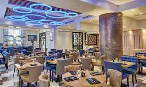 En restaurang med bord och stolar, modern inredning och dekorativ belysning. (AI-genererad text)