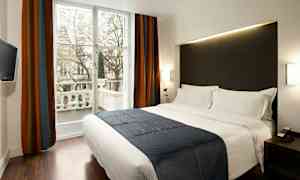 Ett modernt hotellrum med en stor säng, mörka gardiner och ett fönster som vetter mot en balkong. (AI-genererad text)