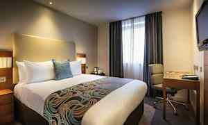 Hotellrum med en stor säng, skrivbord och stol. (AI-genererad text)