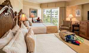 Hotellrum med två bäddar, elegant inredning och ljusinsläpp från ett fönster med utsikt över grönska. (AI-genererad text)