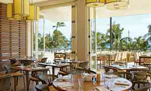 En restaurang med uteservering och utsikt över palmer och hav. (AI-genererad text)