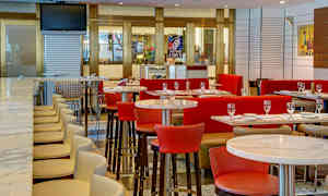 Ett modernt restauranginteriör med bord, stolar och en bar med höga stolar. (AI-genererad text)