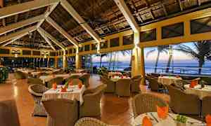 En restaurang med rottingmöbler, dukade bord och havsutsikt. (AI-genererad text)