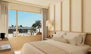 Ett hotellrum med modern inredning och en dubbelsäng. Fönstret visar en balkong med sittmöbler. (AI-genererad text)