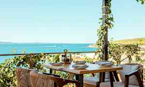 Uteservering med bord och stolar vid havet. (AI-genererad text)