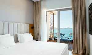 Bild på ett hotellrum med säng och en balkong med utsikt över havet. (AI-genererad text)