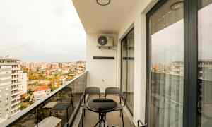 En balkong med ett bord och stolar, med utsikt över en stad. (AI-genererad text)