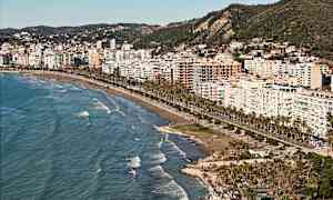 Vy över en stad vid stranden med höga byggnader och havet i förgrunden. (AI-genererad text)