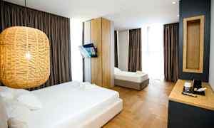 Ett hotellrum med två sängar, en hängande lampa, en väggmonterad TV och ett skrivbord med kaffekokare. (AI-genererad text)