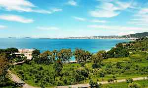 Vy över en kuststad med hav och grönska. (AI-genererad text)