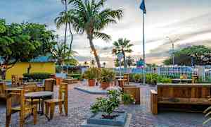 En utomhusmiljö med bord och stolar samt palmer och annan grönska. (AI-genererad text)