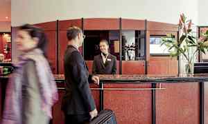 Reception i en hotelllobby med en gäst och en receptionspersonal. (AI-genererad text)