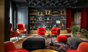 Elegant lounge med röda och svarta möbler, växter och en hylla med dekorativa föremål. (AI-genererad text)